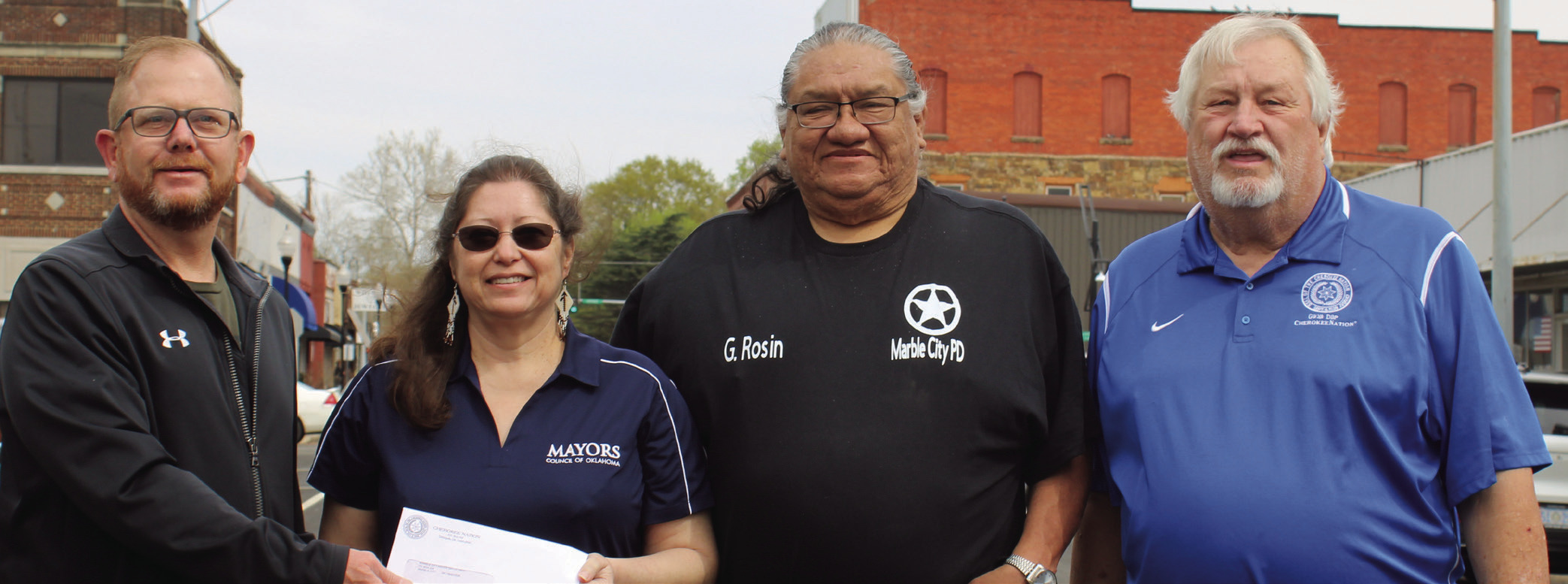 Marble City Mayor Tamara Hibbard holding a check for $10,000 the town received on behalf of their police department on Wednesday from Cherokee Nation Councilmen Daryl Legg, left, and E.O. Smith Jr. (right). Pictured next to Hibbard is Marble City Assistant Chief of Police Eddie Rosin.
