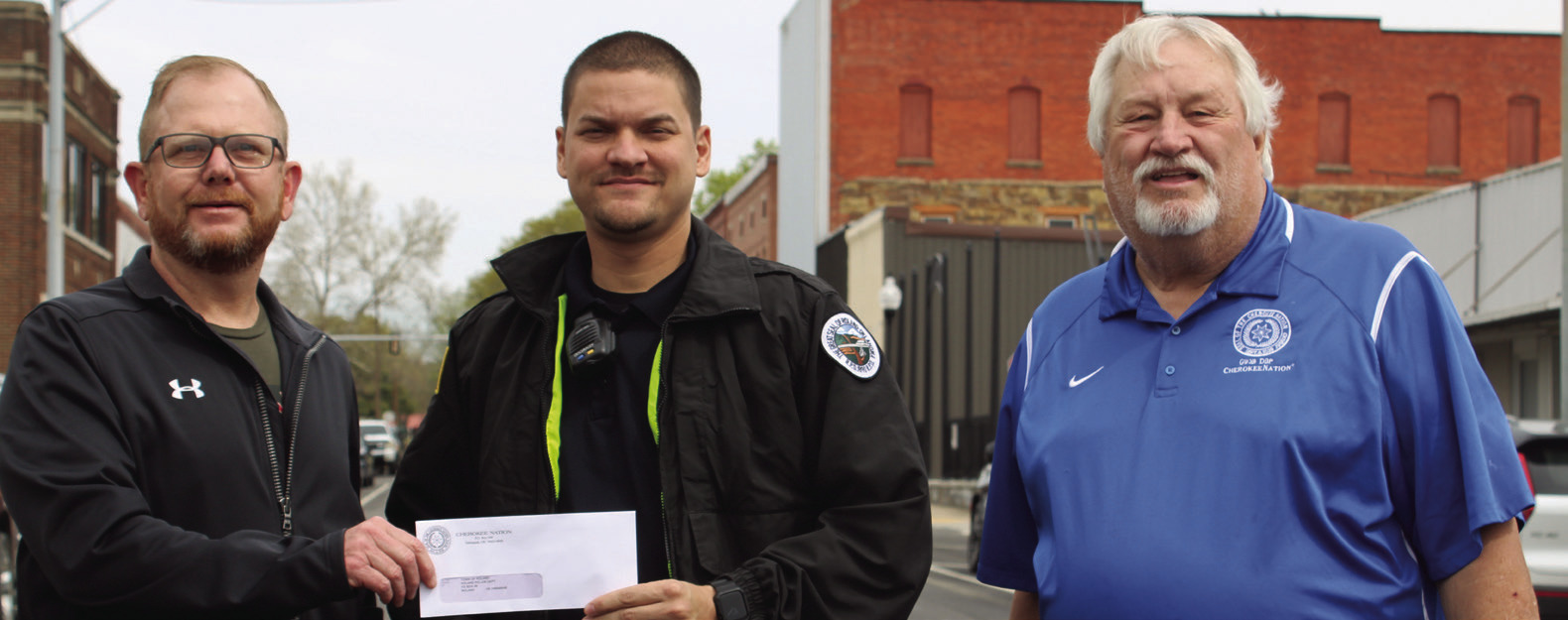 Roland Assistant Police Chief Chris Waters was among several law enforcement agencies from Sequoyah County who received a check from the Cherokee Nation on Wednesday. Presenting the checks were Cherokee Nation Council representatives Daryl Legg (left), and E.O. Smith Jr. (right).